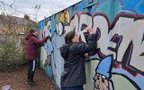 Two people from the group painting large storage container at the allotment 