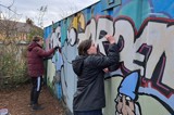 Two people from the group painting large storage container at the allotment 