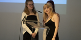 Two young people on the podium presenting at The Key Awards 2024