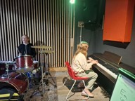 Ava playing drums, Harriet playing piano